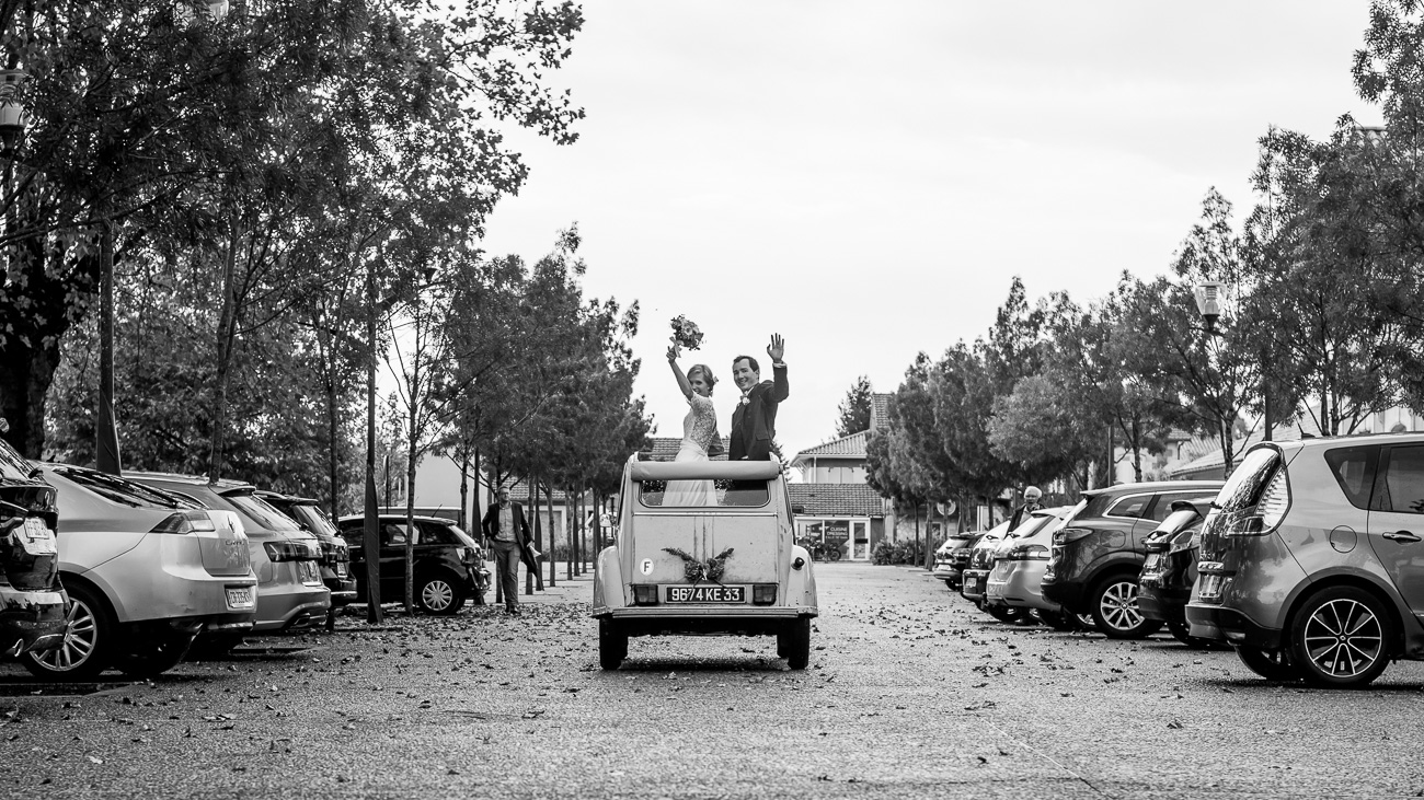 Mariés qui partent avec une vieille voiture